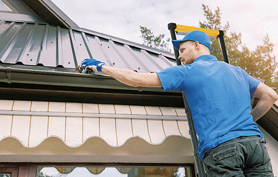 comerciante está consertando o telhado da casa com escada de alumínio telescópica