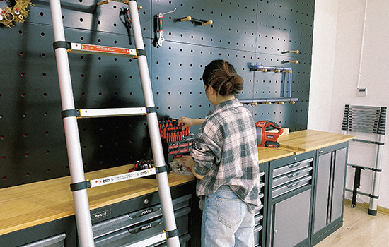Uma garota está separando suas ferramentas de hardware com uma escada telescópica de fecho suave próxima